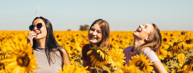 Tree women laughing on a sunflower field